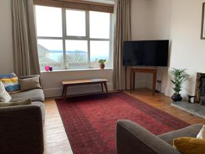 a living room with a television and a red rug at The Post House in Charlestown