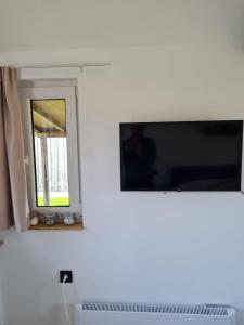 einen Fernseher an einer Wand neben einem Fenster in der Unterkunft 't Hûske in Venhorst