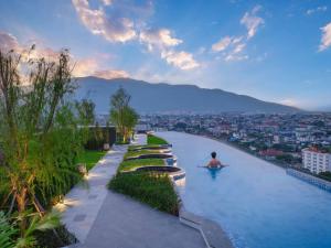 a man sitting in a infinity pool at a resort at Amazing View The Astra Sky River, Chiang Mai in Chiang Mai