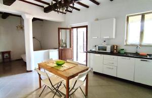 cocina con mesa de madera y armarios blancos en Poggio alla Pietra 26, en Porrona