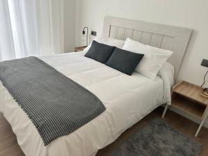um quarto com uma cama branca e almofadas pretas em Apartamento Vigo Centro Puerta del Sol em Vigo