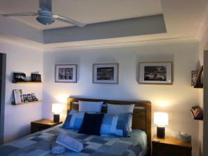 a bedroom with a bed with blue and white pillows at WAVE N' SOUL in Dunsborough