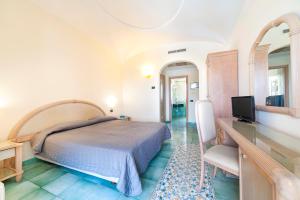 a bedroom with a bed and a desk with a television at Hotel Terme Don Pepe in Ischia