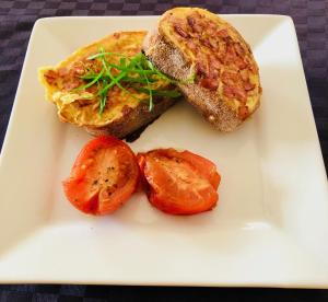 a white plate with a sandwich and tomatoes on it at WAVE N' SOUL in Dunsborough