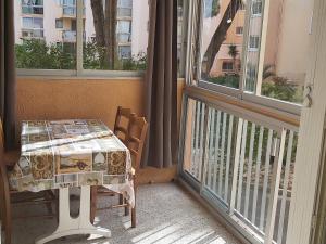 Zimmer mit einem Tisch und einem Balkon mit Fenstern in der Unterkunft Appart Familial Le Grau Du Roi in Le Grau-du-Roi