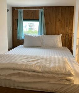 a large bed with white sheets and a window at B475house in Nha Trang