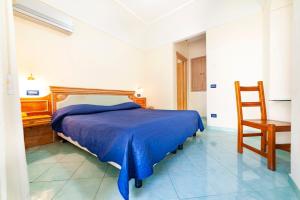 um quarto com uma cama azul e uma cadeira de madeira em Hotel Terme Don Pepe em Ischia