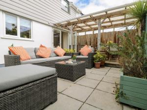 un patio con muebles de mimbre y pérgola en Chy Kerris, Carbis Bay, en Carbis Bay