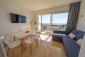 a living room with a blue couch and a table with chairs at AR Apartaments Camps in Blanes