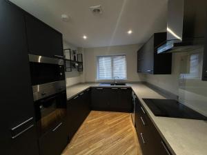 a kitchen with black appliances and a wooden floor at Apartment in Birkdale - 2 bedrooms in Southport