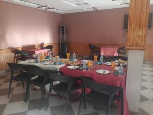 una sala da pranzo con tavoli, sedie e pareti rosa di ESPACE INOV IMILCHIL a Imilchil
