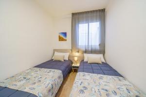 two beds in a room with a window at AR Apartaments Camps in Blanes