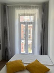 a bed with two pillows in front of a window at Pérola do Ar - Estúdio no coração de Setúbal in Setúbal