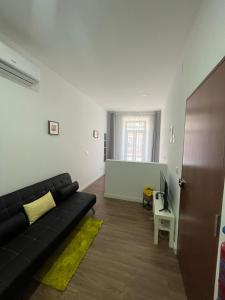 a living room with a black couch and a television at Pérola do Ar - Estúdio no coração de Setúbal in Setúbal