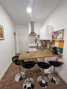 a kitchen with a counter and four bar stools at Pérola do Ar - Estúdio no coração de Setúbal in Setúbal
