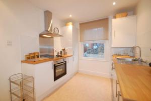 uma cozinha com armários brancos, um lavatório e uma janela em Estuary View Apartment em Deganwy