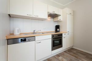 a kitchen with white cabinets and a sink at Residenz Bel Vital Wohnung 41 in Binz