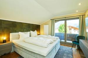 ein großes weißes Bett in einem Zimmer mit Fenster in der Unterkunft Haus Almrose in Reit im Winkl