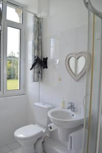 La salle de bains blanche est pourvue de toilettes et d'un lavabo. dans l'établissement Château de KERVOAZEC - Chambres d'hôtes, à Saint-Goazec