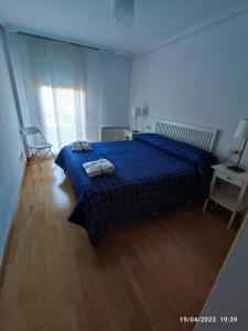 a bedroom with a blue bed with two towels on it at Apartamento La Bien Cercada in Zamora