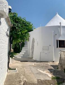 a white building with stairs and a tree next to it at Trullibellula in Alberobello