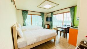 1 dormitorio con 2 camas, escritorio y mesa en Billions Motel, en Gangneung