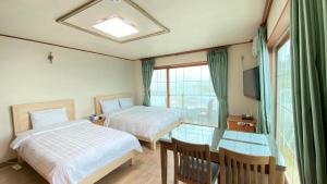 a hotel room with two beds and a glass table at Billions Motel in Gangneung