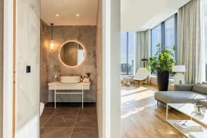 a bathroom with a sink and a living room at NH Collection Copenhagen in Copenhagen
