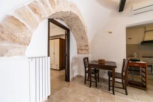 a kitchen with an archway and a table and chairs at Trullibellula in Alberobello