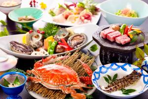 a table topped with plates of seafood and other dishes at Tara Dakeonsen Kanigoten in Tara