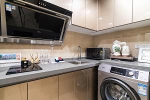 a kitchen with a washing machine and a microwave at Cloud Land Apartment 翡翠华庭 in Guangzhou