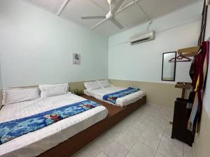 a bedroom with two beds and a ceiling fan at Ipoh Canning Garden Simple House 4R3B 12pax SY19 in Ipoh