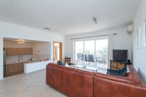 a living room with a brown leather couch and a kitchen at Apartment Avoca in Cavtat