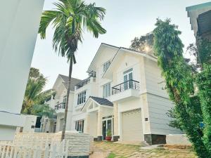 a white house with a palm tree in front of it at The Beachhouse Villa- 4 bedrooms Villa- 5' to Bai Sau Beach in Xã Thang Tam