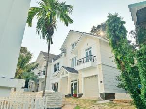 una casa blanca con una palmera delante en The Beachhouse Villa- Biệt Thự 4 Phòng Bãi Sau- 4 bedrooms Villa- 5' to Bai Sau Beach, en Xã Thang Tam