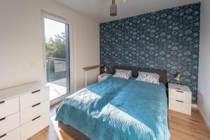 1 dormitorio con 1 cama con edredón azul en SEA Apartment Porto Łeba, en Łeba