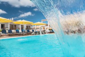 een waterglijbaan in een zwembad met stoelen en parasols bij Spa & Sport Hotel Mar y Sol in Arona