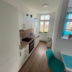 Oschatz的住宿－Moderne Gästewohnung "Am Weinberg"mit Terrasse，厨房配有白色橱柜和绿色椅子