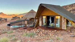 a house in the desert with a thatched roof at Namib Outpost in Sesriem