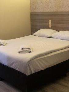 a large bed with white sheets and towels on it at Hotel My Rose in Batumi