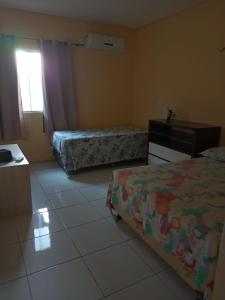 1 Schlafzimmer mit 2 Betten, einer Kommode und einem Fenster in der Unterkunft Casa Praia Luís Correia in Luis Correia