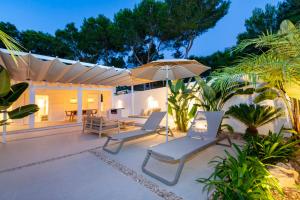 a patio with two chairs and an umbrella at Ses Eufabietes Apartments & Restaurant in Sant Francesc Xavier