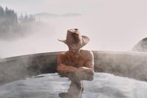 a man in a cowboy hat sitting in a hot tub at Górna Chata Mountains Chalet - Stable Cottage in Ochotnica Górna