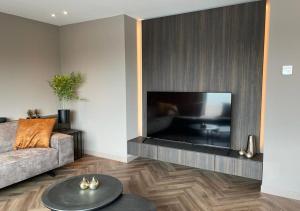 a living room with a couch and a large television at Villa Lands End Stavoren in Stavoren