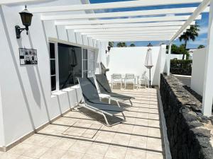 un patio con sillas y una mesa en un edificio blanco en Casas Maribel Pocillos - No Pool - Sin Piscina, en Puerto del Carmen