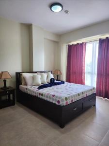 a large bed in a room with two windows at SERIN WEST TAGAYTAY-Spacious & Comfy 2BR Unit with Parking and Balcony in Tagaytay