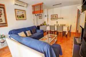 ein Wohnzimmer mit einem blauen Sofa und einem Tisch in der Unterkunft Oasis Sinia by Hello Homes Sitges in Sitges