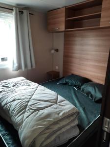 ein unmaskiertes Bett in einem Schlafzimmer neben einem Fenster in der Unterkunft MOBIL HOME LE FAMILIAL in Valras-Plage
