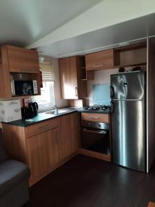 eine Küche mit einem Kühlschrank aus Edelstahl und Holzschränken in der Unterkunft MOBIL HOME LE FAMILIAL in Valras-Plage