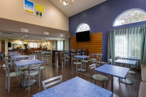 un restaurante con mesas, sillas y TV en Days Inn & Suites by Wyndham Cherry Hill - Philadelphia, en Cherry Hill